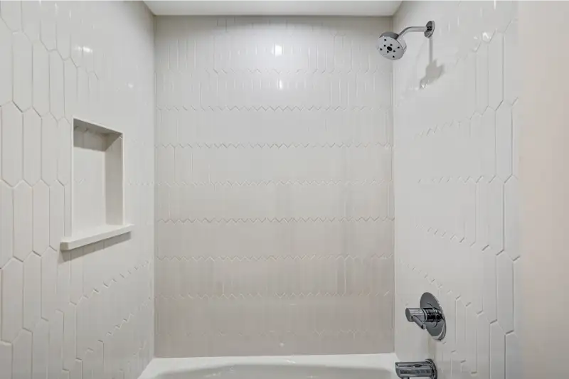 Custom tiled walk-in shower with built-in niche and premium plumbing fixtures in a luxury townhome bathroom