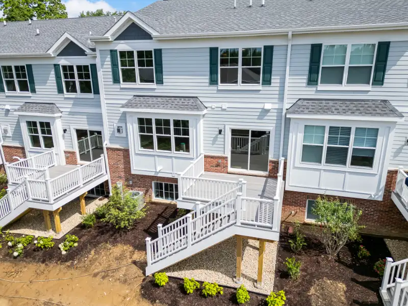 Aerial rear view of luxury townhomes with private decks, landscaping, and premium architectural details